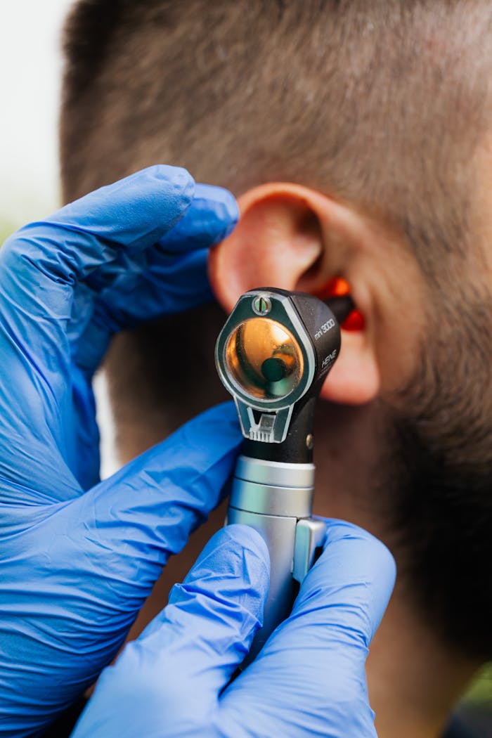 Close-up of a doctor using an otoscope to examine a patients ear.